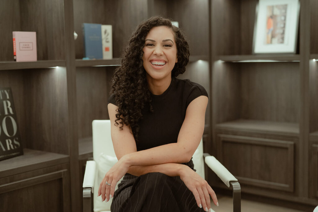 Woman in black dress smiling at the Camera