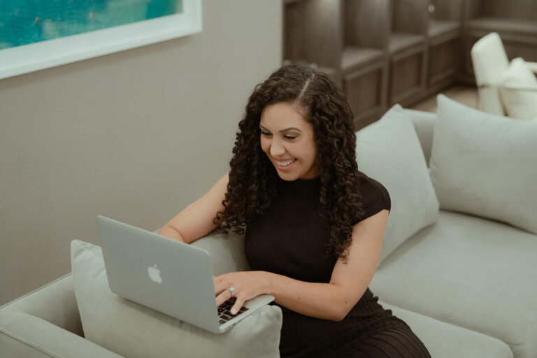 Woman in black dress typing on a laptop